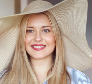 Woman, fashion and summer country charm, blonde beauty and elegance in wide brimmed beach hat. Feminine allure, timeless style and graceful glow. Smile, straw hat and blue striped blouse, natural lighting and effortless charm, fashion look idea