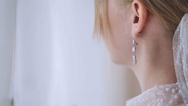 Bride wearing delicate pearl earrings, complementing bridal attire with sophisticated elegance