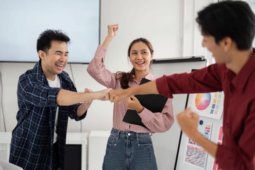 Celebrating a moment of triumph, team members exchange fist bumps in a collaborative workspace, reflecting unity and shared accomplishment in their project.