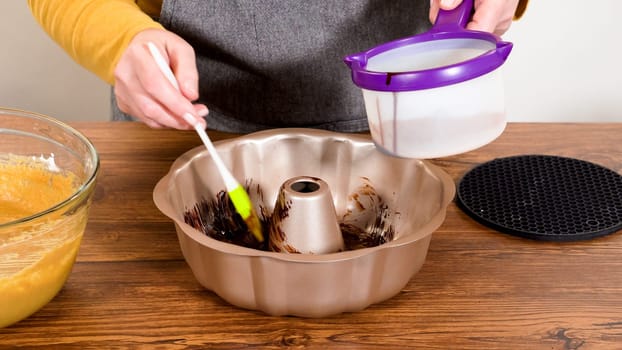 Carefully greasing a bundt cake pan in preparation for baking a delicious gingerbread bundt cake with caramel frosting.