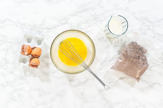 Flat lay. In the process of creating mouthwatering chocolate cupcakes, the first step involves meticulously mixing the ingredients in a glass mixing bowl to make the perfect batter.