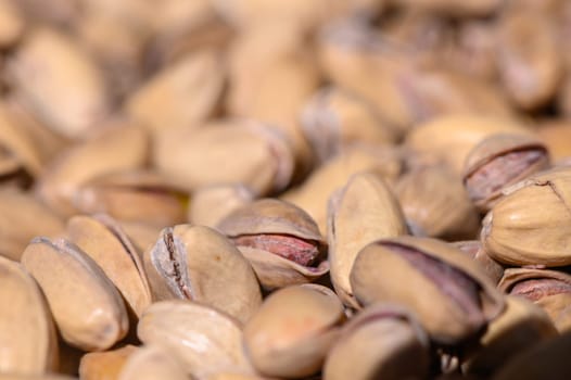 Pistachio nuts are scattered across a surface, showcasing their distinct green and beige hues under soft natural light.