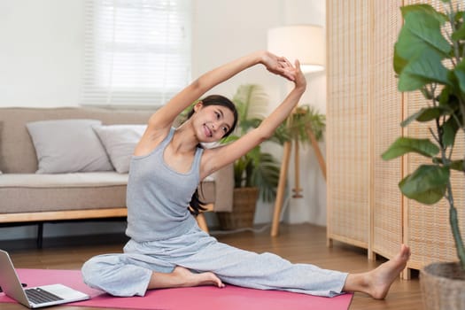 With a relaxed expression, a woman performs side bends on her yoga mat, embracing flexibility and tranquility in her stylish living space.