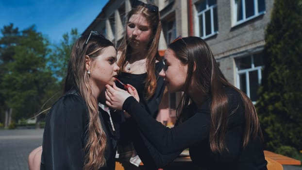 High school students enjoying their break outdoors, applying makeup and sharing laughs while embracing friendship and youthful beauty
