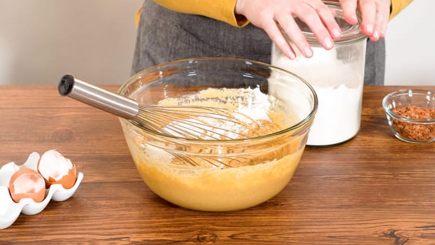 In a glass mixing bowl, a large hand whisk expertly blends the ingredients for a delectable gingerbread bundt cake with caramel frosting.
