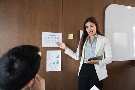 In an interactive session, a business professional leads a presentation on project management, effectively communicating insights and engaging with the team.