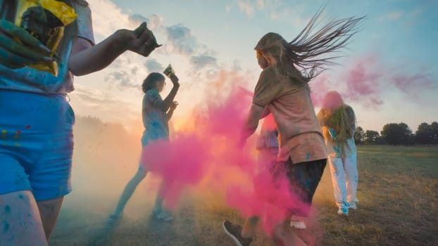 Young people enjoying holi festival, throwing colored powder at sunset, and having a blast together