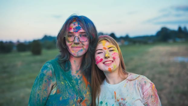Two joyful young women, adorned in colorful holi powder, share a loving embrace at a festival, reveling in the bond of friendship and the vibrant hues of the celebration