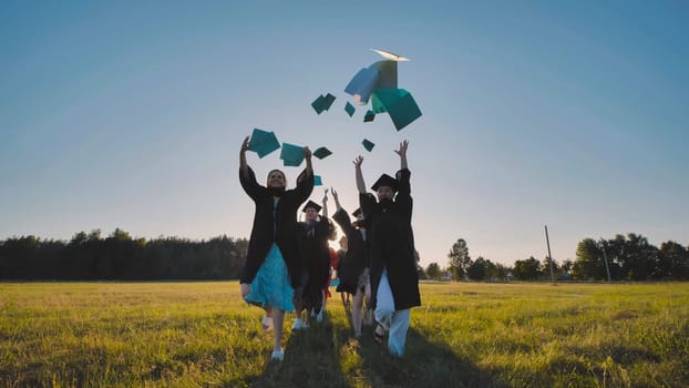 Group of happy graduates throwing diplomas in the air at sunset, celebrating their academic achievement