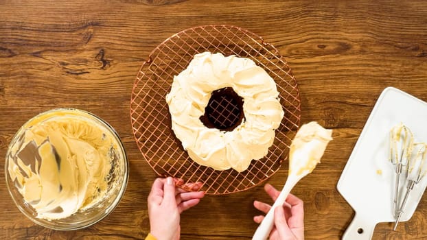 Flat lay. A gingerbread bundt cake being generously frosted with salted caramel frosting and topped with delightful gingerbread sprinkles.