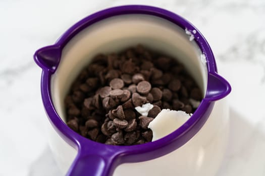 Chocolate chips and butter placed in a purple melting pot, ready to be heated for creating a rich chocolate dip.
