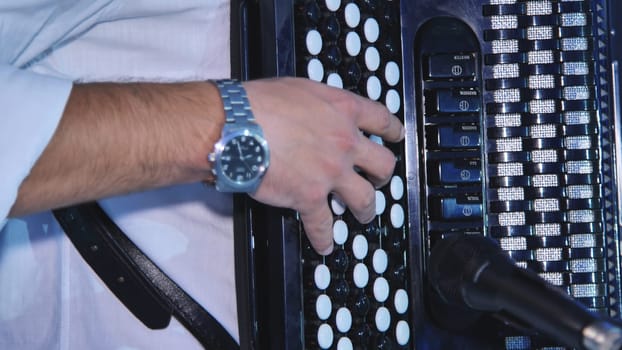 Close up of musician's hand playing a black and white accordion during a wedding celebration