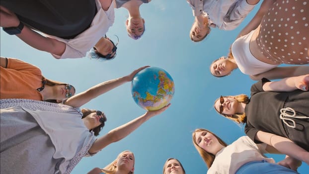 Group of school friends forming a circle, holding a globe together, symbolizing their commitment to environmental protection and global unity