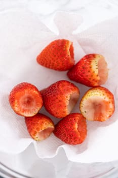 Freshly washed and dried strawberries are carefully arranged in a glass bowl lined with paper towel, ready for snacking or further use.