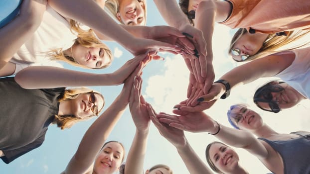 Group of school friends forming a circle with their hands, symbolizing unity, teamwork, and collaboration