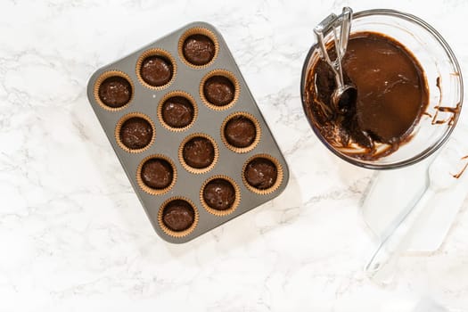 Flat lay. The process involves carefully scooping the rich batter into the waiting cupcake pan.