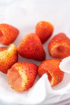 Freshly washed and dried strawberries are carefully arranged in a glass bowl lined with paper towel, ready for snacking or further use.