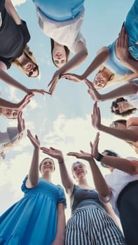 Group of school friends forming a circle with their hands, symbolizing their strong bond, unity, and teamwork against a cloudy sky