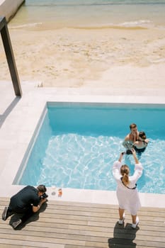 Photographers take pictures from different angles of man hugging woman in a swimming pool. Drone. High quality photo