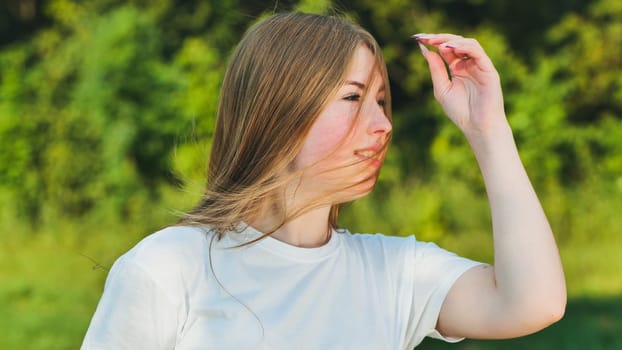 Young woman shielding her eyes from the sun with her hand while looking at something in the distance in nature