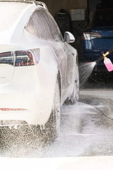 Efficiently cleaning an electric car in the comfort of a suburban driveway, combining eco-consciousness with practicality.
