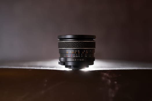 Lens for a film camera stands on a black table. High quality photo