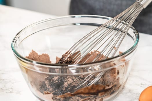 In the process of creating mouthwatering chocolate cupcakes, the first step involves meticulously mixing the ingredients in a glass mixing bowl to make the perfect batter.