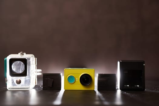 Yellow Xiaomi Y1 action camera with frame, charger and replaceable batteries stands on the table. High quality photo