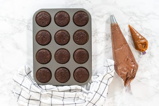 Flat lay. Just out of the oven, these delectable chocolate cupcakes are now resting and cooling on the kitchen counter, filling the air with their tempting aroma.