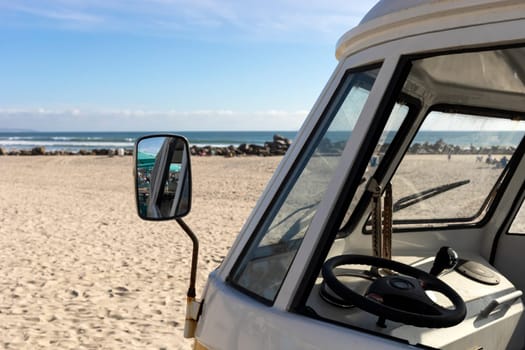 Window With Mirror Of Orange Camper Van Parked In The Seashore, Yellow Sand And Water, Ocean Line On Background, Travel Destination, Summer And Vacation. Horizontal. High quality photo
