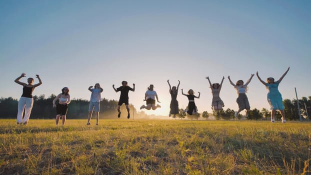 Group of cheerful high school students enjoying their summer break, jumping joyfully in a field at sunset
