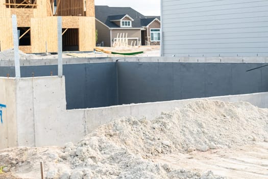 An ongoing construction site in the suburbs, featuring the foundation stage of a single-family house.