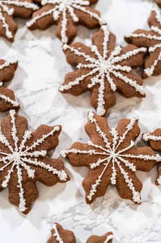 Detailed view of chocolate ginger snowflake cookies decorated with royal icing, arranged on a light background, perfect for holiday festivities.
