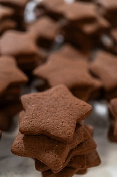 A close-up view of a neatly stacked pile of gingerbread star cookies, emphasizing their rich, spiced texture and perfect shape.