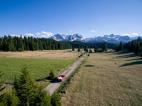 Bride and groom are driving along the highway in the mountains in a cabriolet. Drone. High quality photo