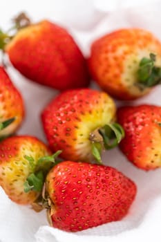 Freshly washed and dried strawberries are carefully arranged in a glass bowl lined with paper towel, ready for snacking or further use.