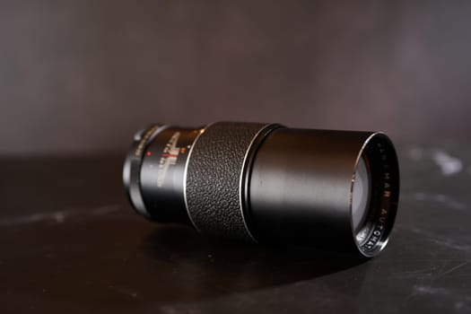 Antique Hanimar Automatic telephoto lens lies on a black table. Side view. High quality photo