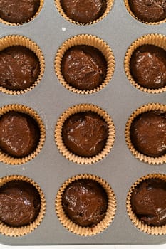 The process involves carefully scooping the rich batter into the waiting cupcake pan.