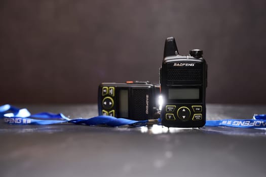 Pair of Baofeng BF-T1 walkie-talkies lies on a black table with blue ribbons. High quality photo
