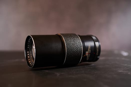 Vintage Hanimar telephoto lens lies on a black table. Side view. High quality photo