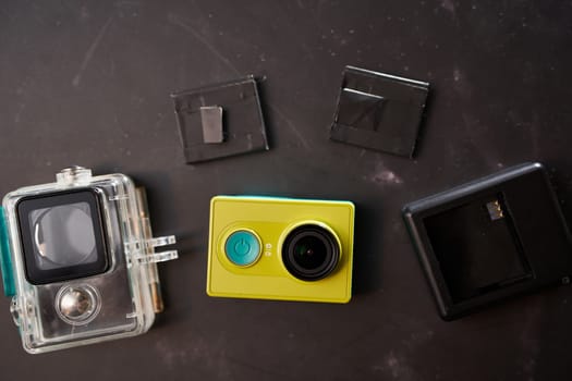 Yellow Xiaomi Y1 action camera with a transparent case, charger and replaceable batteries lies on the table. High quality photo