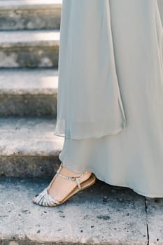 Woman foot in sandals descends the stone steps. Cropped. Faceless. High quality photo