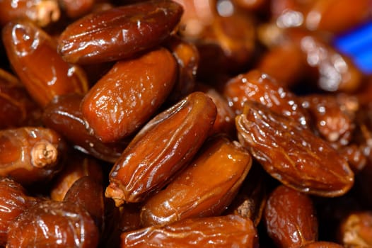 A close-up view reveals clusters of shiny dried dates, their rich brown hue showcasing the natural sweetness. These delectable treats are often enjoyed in various culinary delights.