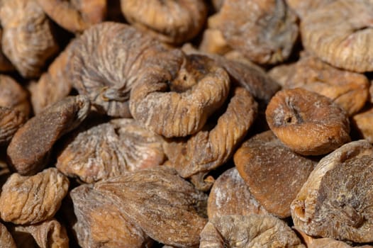 Sunlit dried figs are arranged beautifully in a colorful marketplace, showcasing their wrinkled texture and deep caramel hue. Vendors highlight their natural sweetness, enticing passersby.