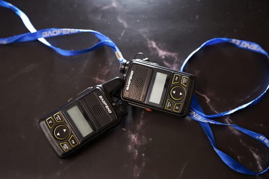 Pair of Baofeng BF-T1 digital portable walkie-talkies lie on a black table with blue ribbons. High quality photo