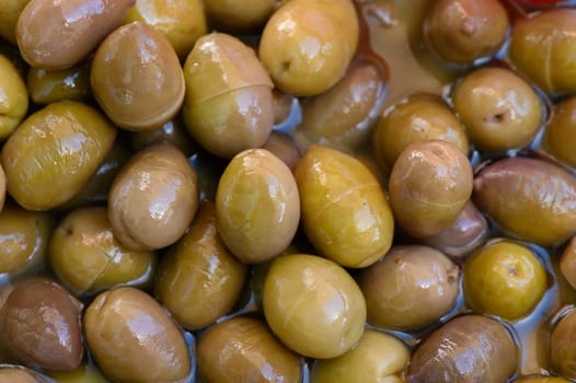 A colorful assortment of olives resting in fragrant oil fills the market stand, offering a glimpse into the rich flavors and textures that delight taste buds.