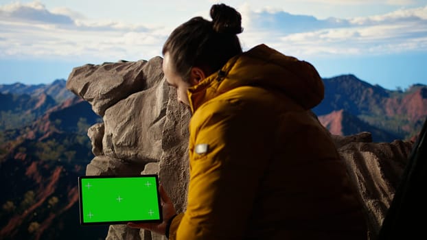Adventure seeker stands at a mountain peak next to isolated chroma key, looking out at the scenic view that stretches endlessly before him. Fresh air and breathtaking landscape. Camera A.