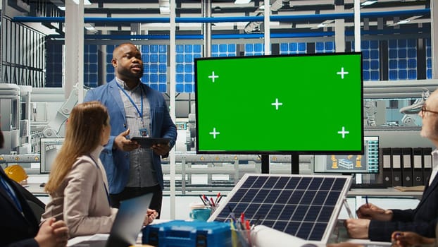 Factory shareholders chat about company growth, looking at green screen monitor. Investors meet with plant executives to improve production, looking at presentation on mockup display, camera A