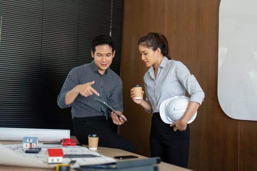 Two engineers engage in a relaxed discussion over coffee, reviewing architectural designs. Their collaboration fosters innovation and project development.