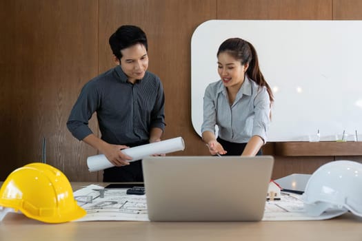 Two colleagues engage in a productive discussion while reviewing blueprints, showcasing teamwork and strategic planning in an engineering environment.